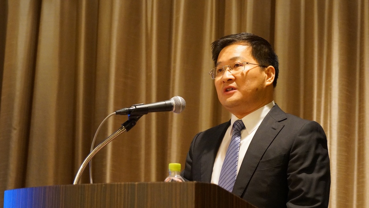 カーテンの前に立っているスーツを着た男性中程度の精度で自動的に生成された説明