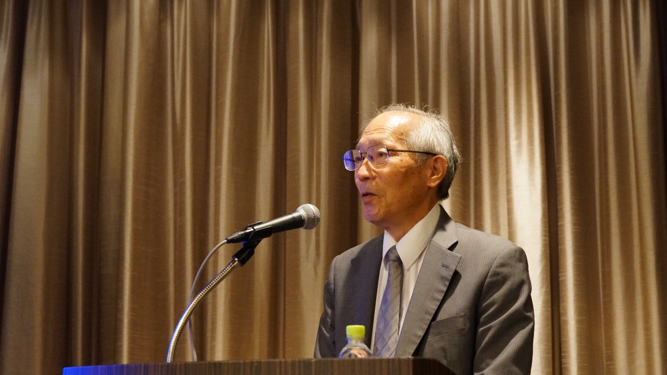 カーテンの前に立っているスーツを着た男性中程度の精度で自動的に生成された説明