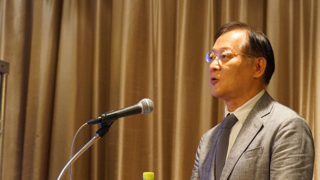 カーテンの前に立つスーツを着た男性中程度の精度で自動的に生成された説明